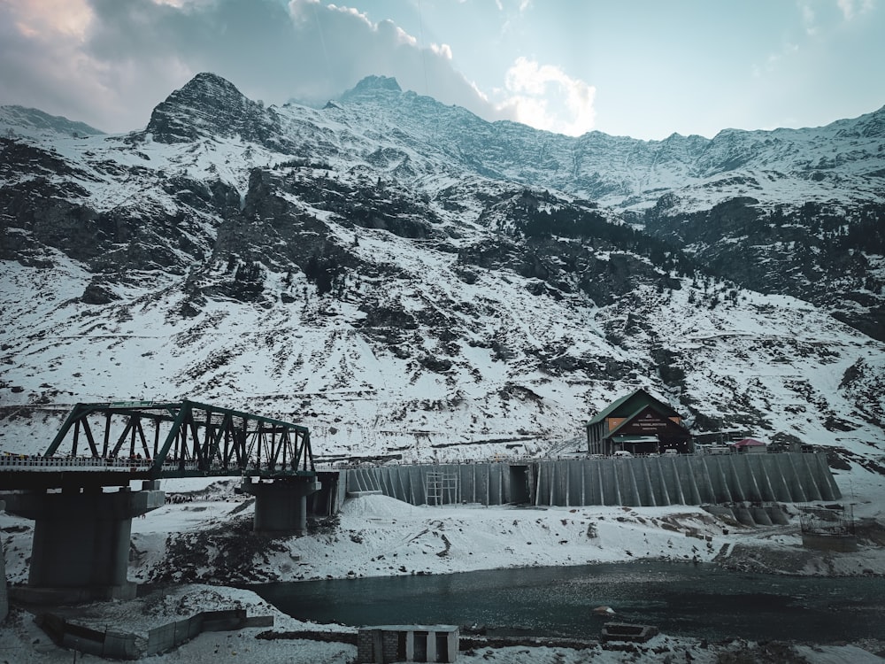 a snow covered mountain with a bridge in the foreground