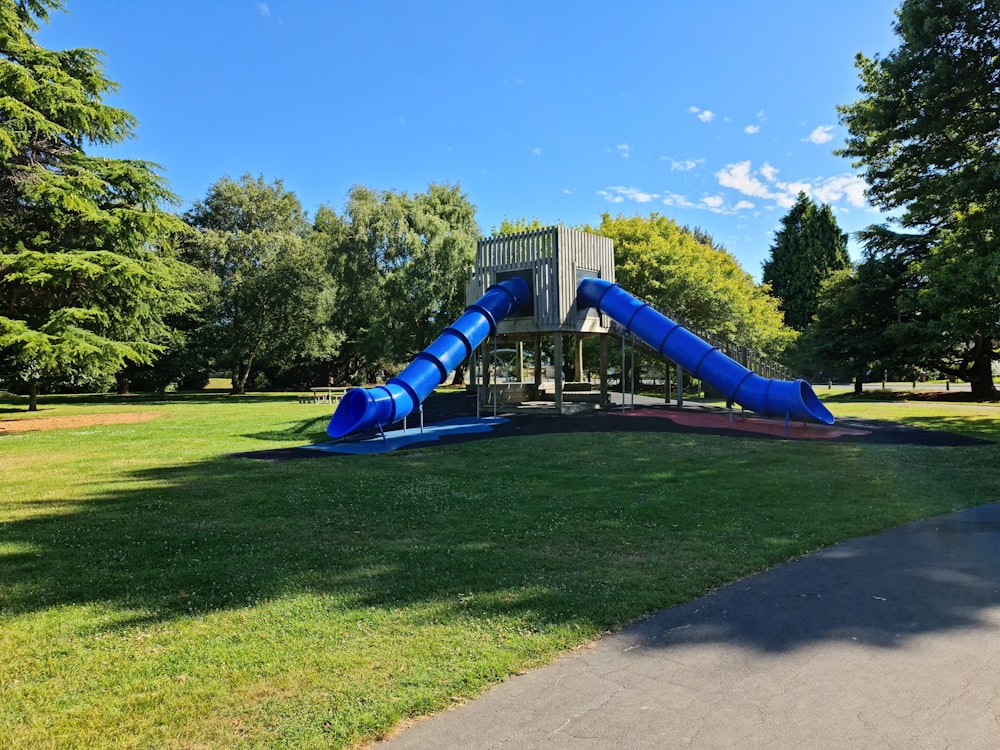 a blue slide in the middle of a park