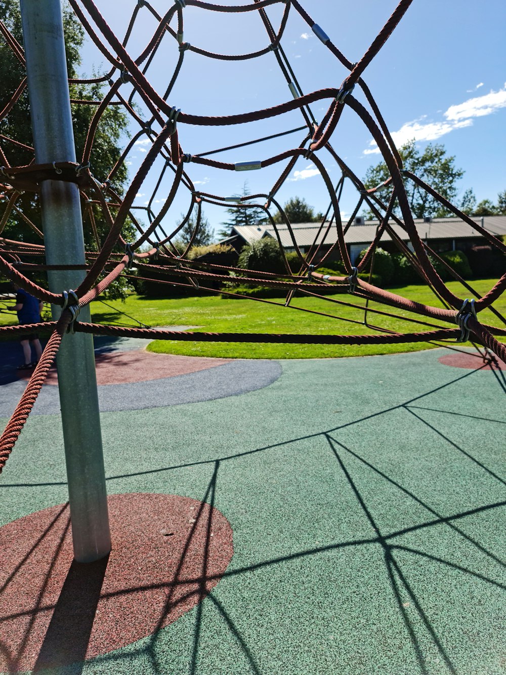 a close up of a playground net with grass in the background