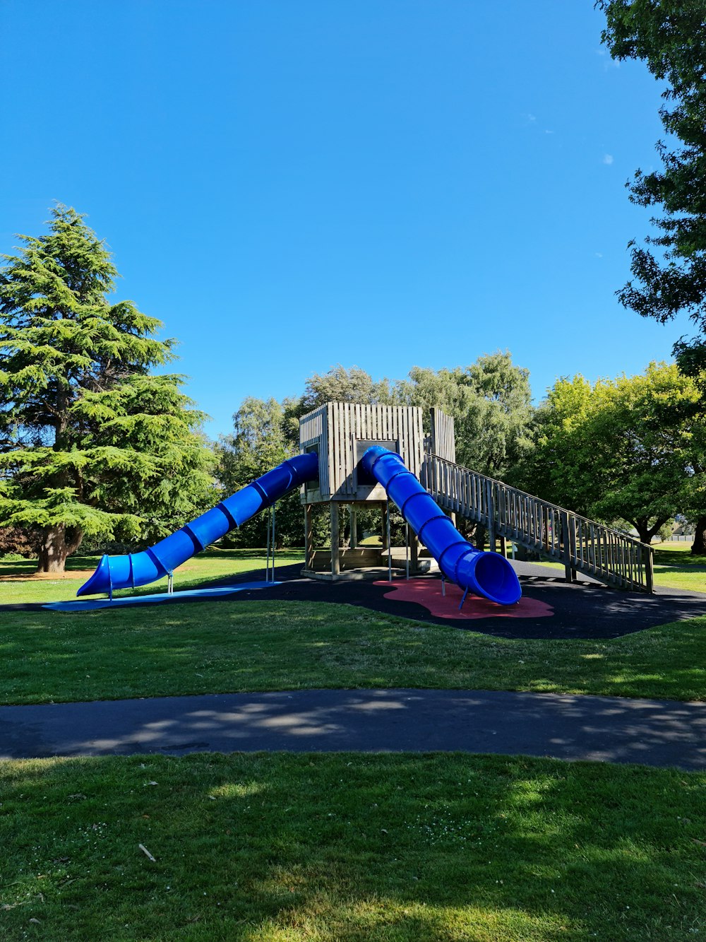 a blue slide in a park with trees in the background