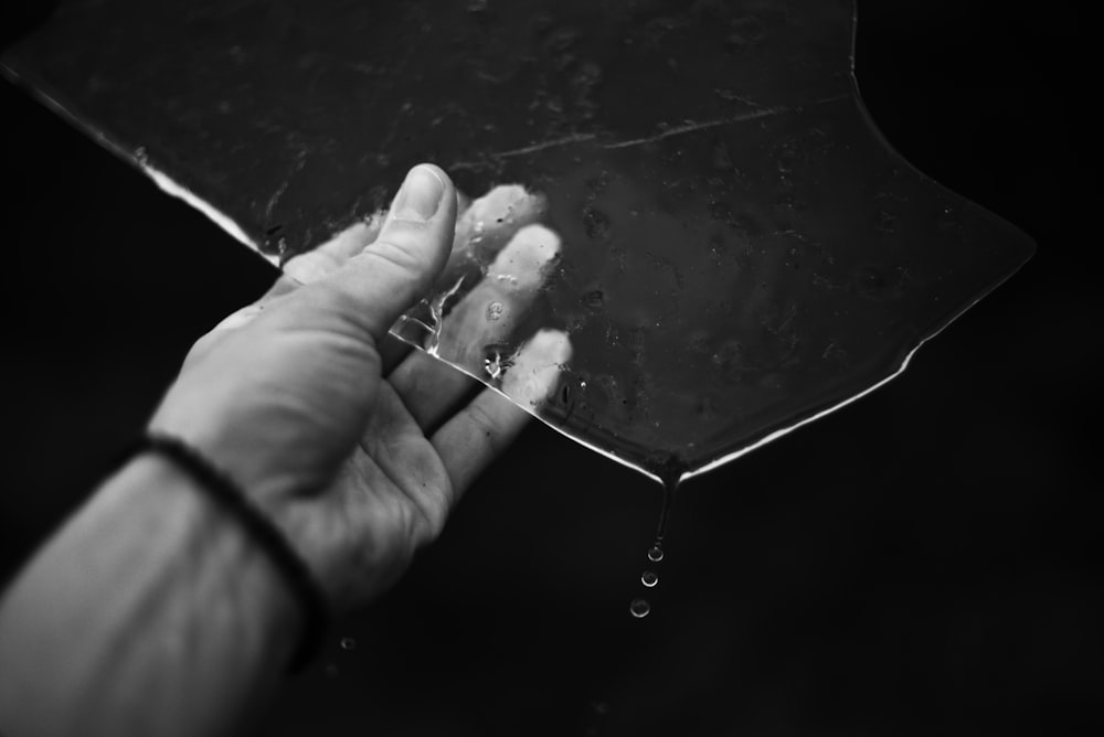 a hand holding an umbrella in the rain