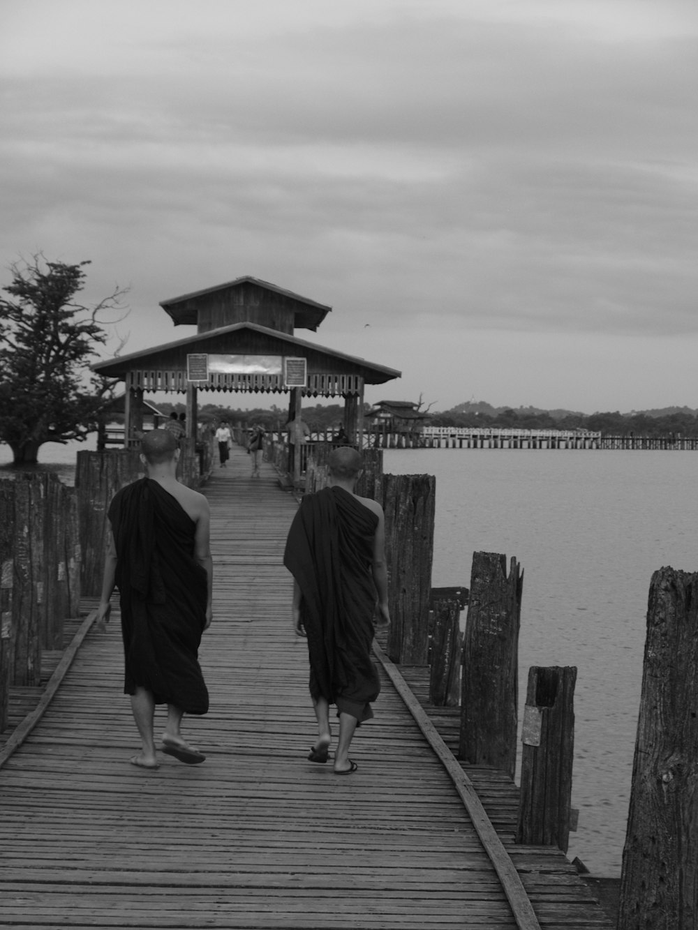 a couple of people walking across a wooden bridge