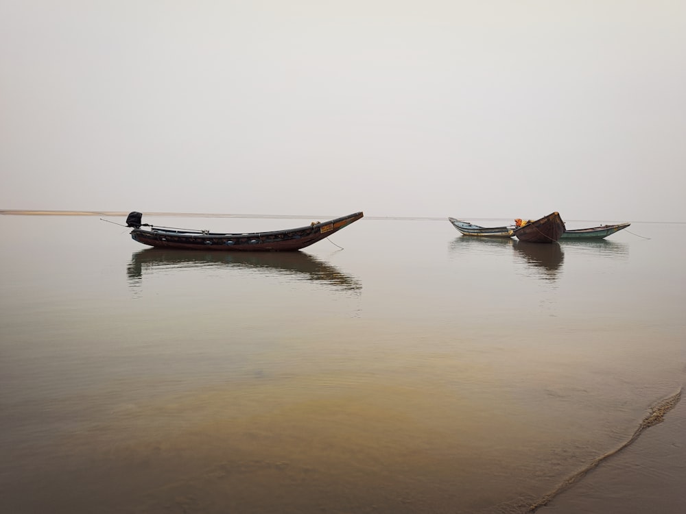 a couple of small boats floating on top of a lake