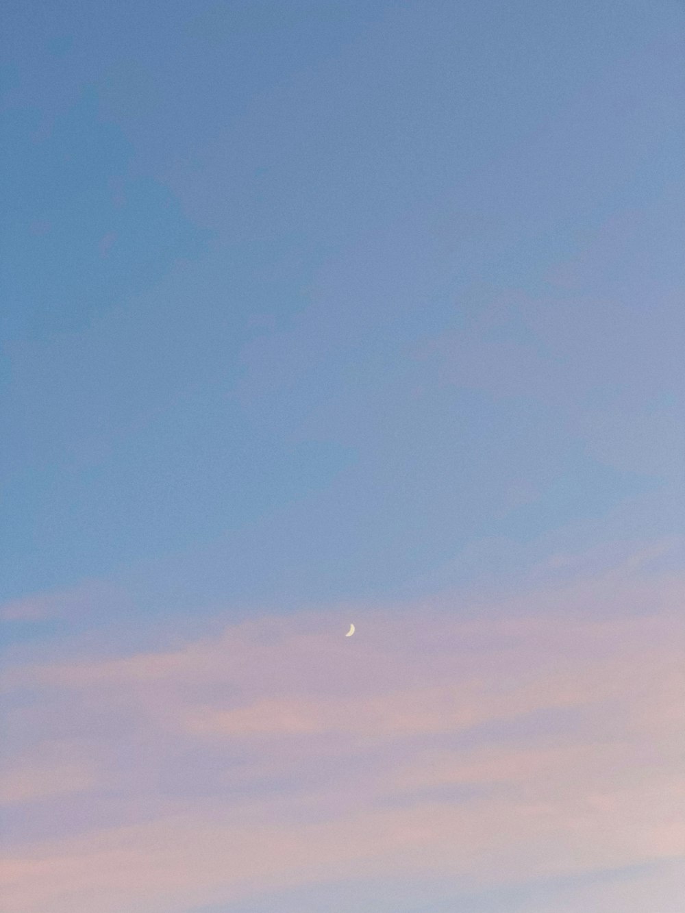a plane flying in the sky with a moon in the distance