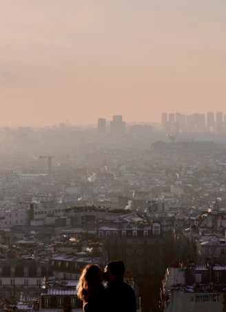 a man and woman standing on top of a tall building