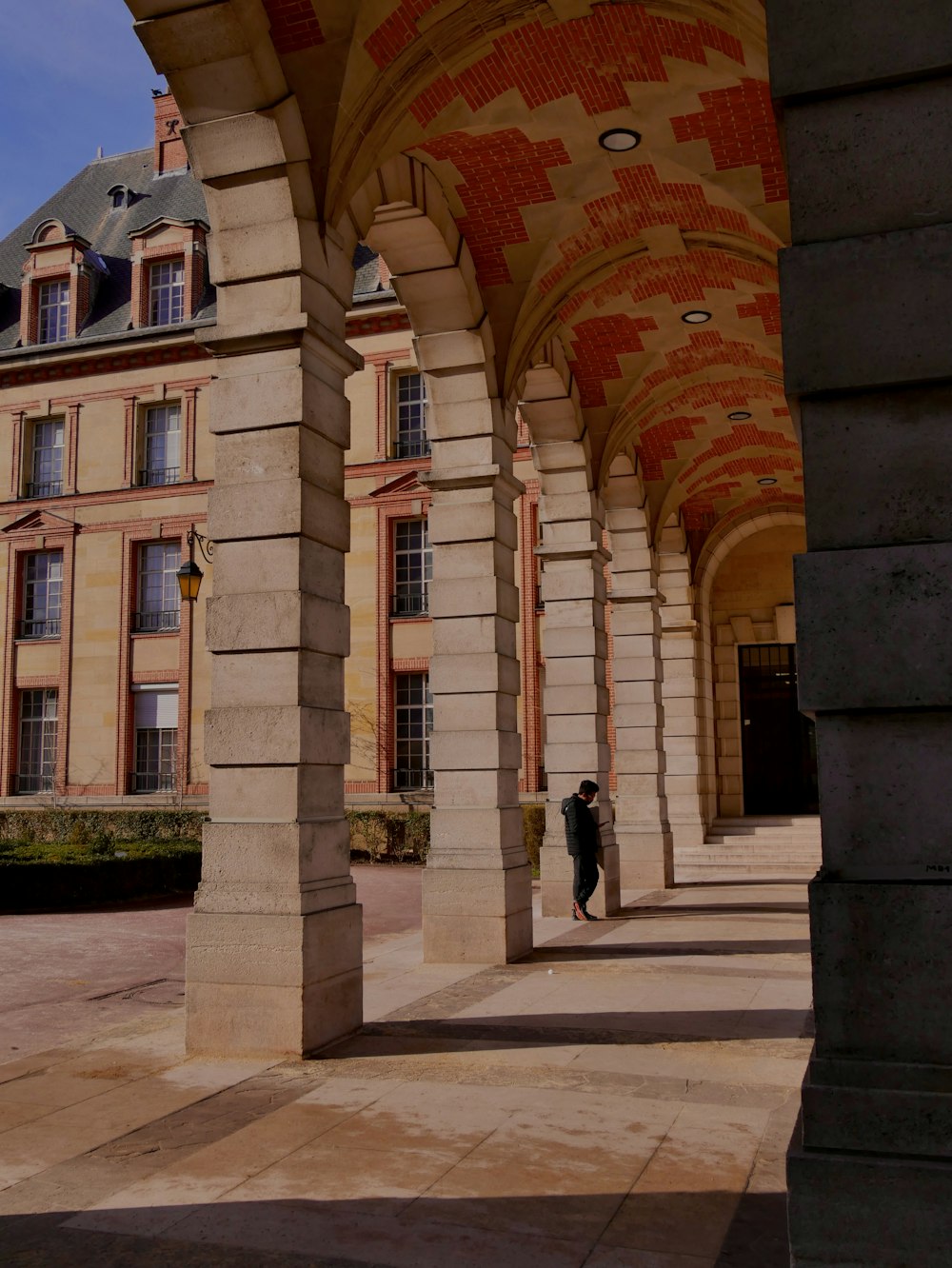 a person is standing under a row of pillars