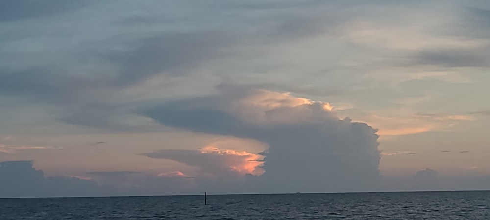 a large cloud in the sky over a body of water