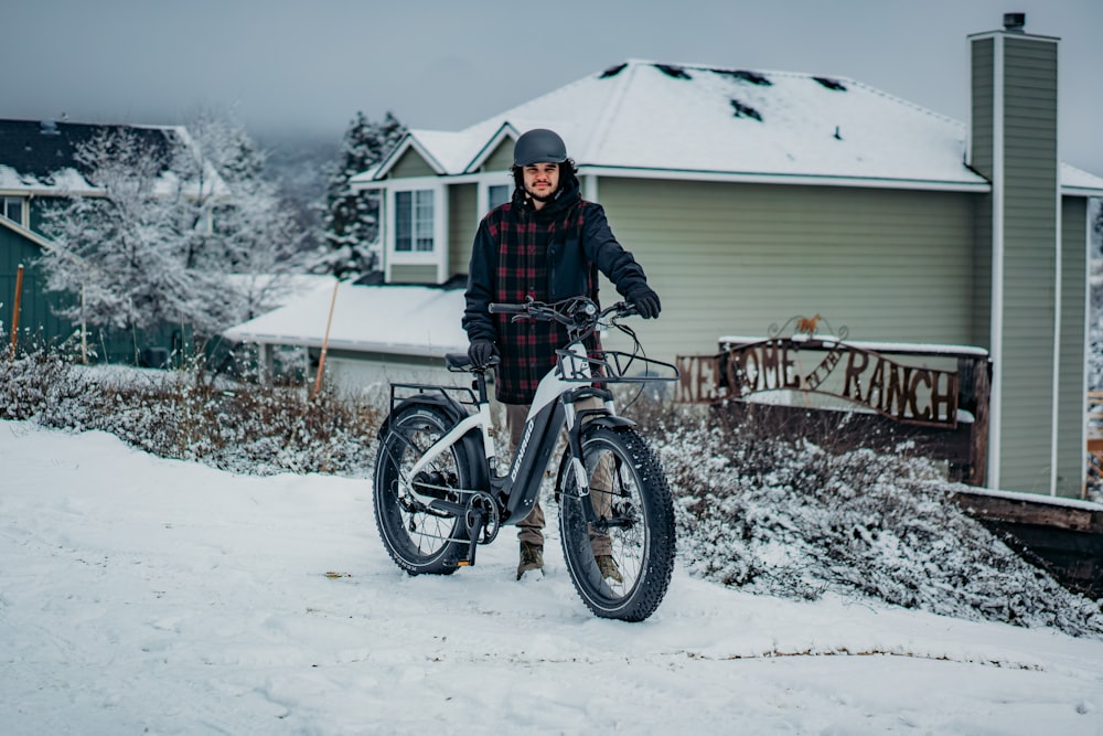 a person standing next to a bike in the snow