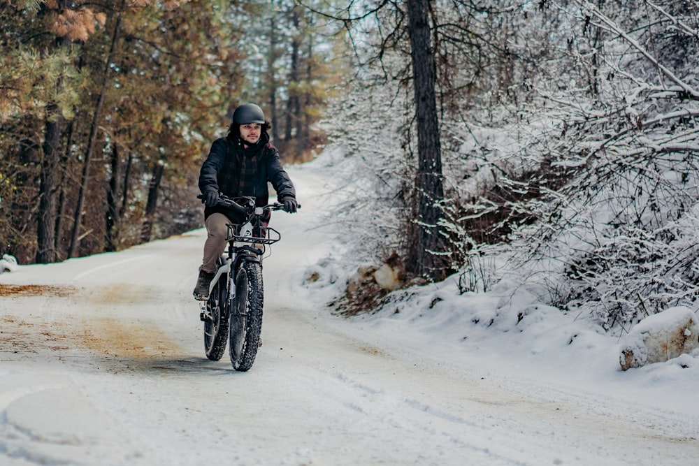 a man riding a bike down a snow covered road