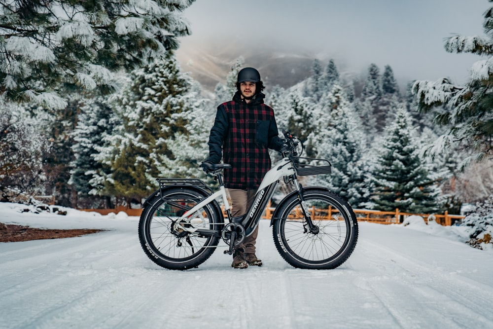 a person standing next to a bike in the snow