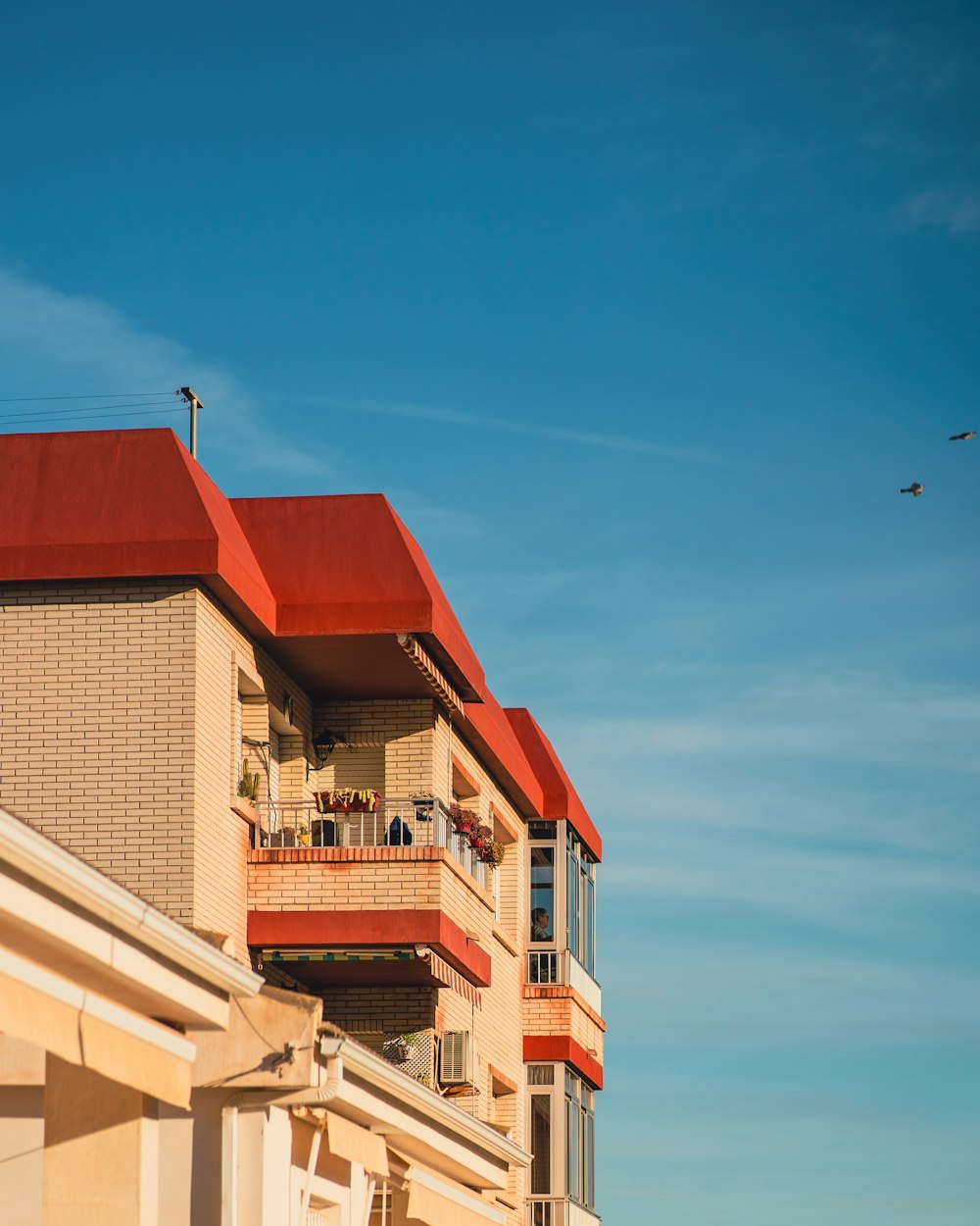 an apartment building with a red roof and balconies