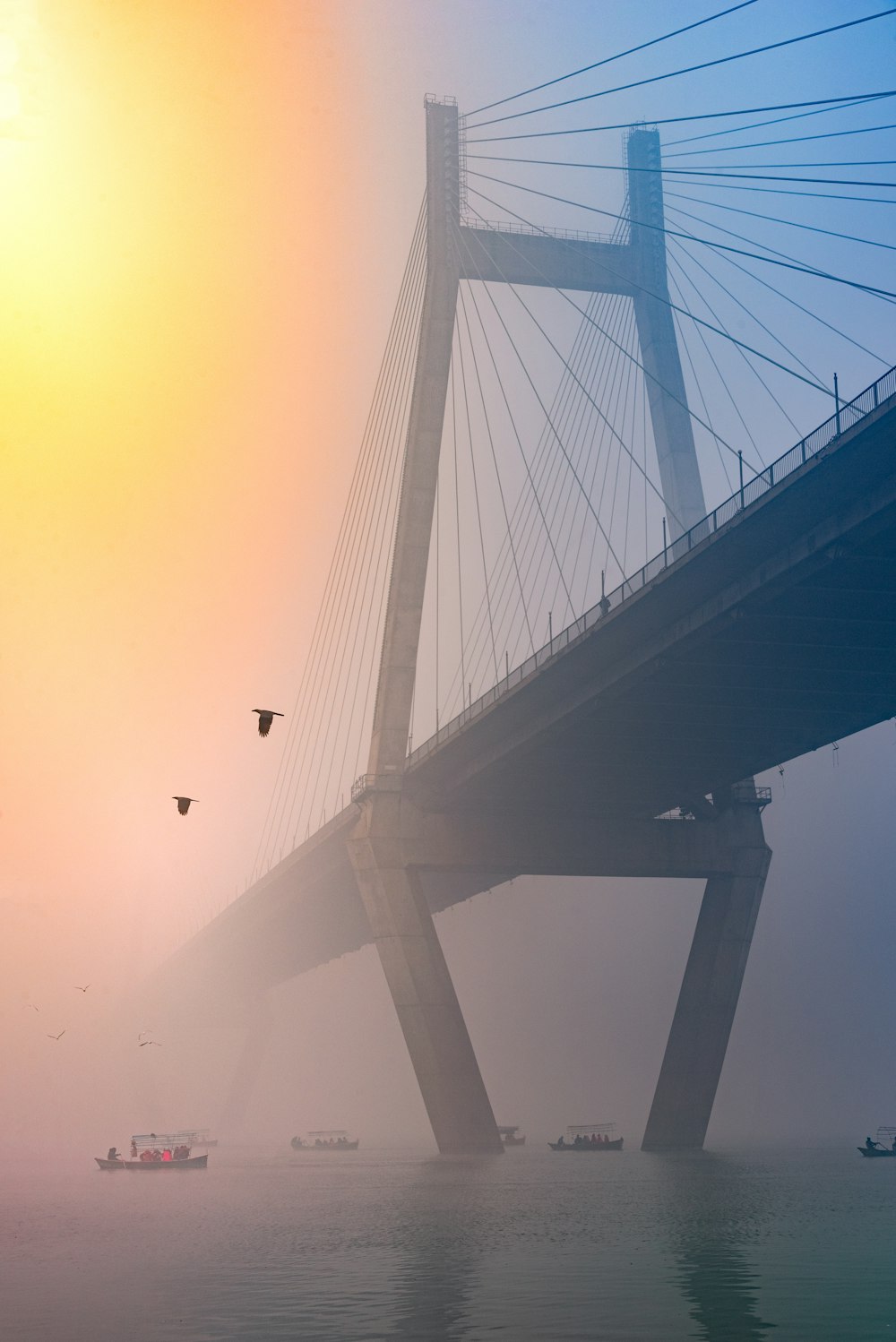 a bridge with birds flying over the water