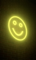 a smiley face neon sign on a brick wall