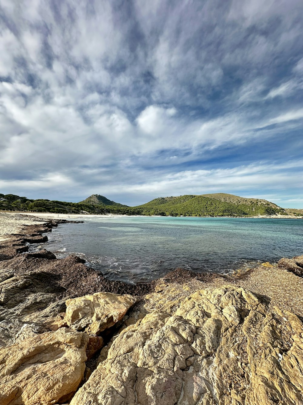 a rocky beach with a body of water in the distance