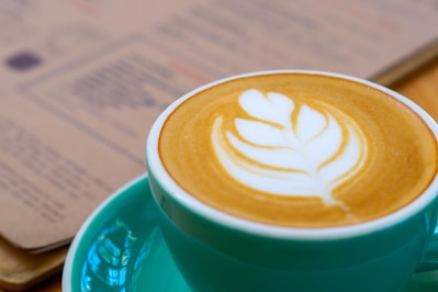 a cup of coffee on a saucer with a book in the background