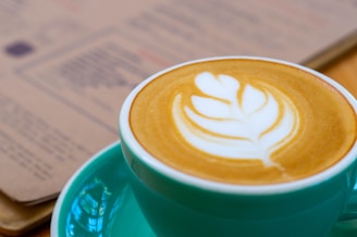 a cup of coffee on a saucer with a book in the background