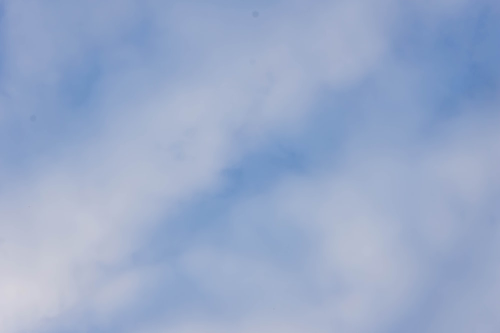 a plane flying in the sky with clouds in the background