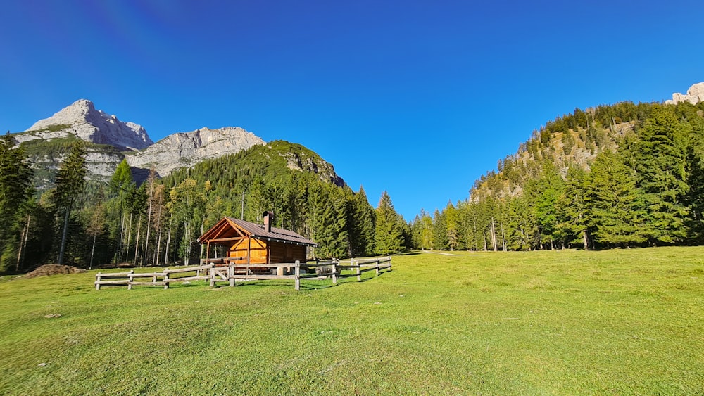 a cabin in a field with mountains in the background