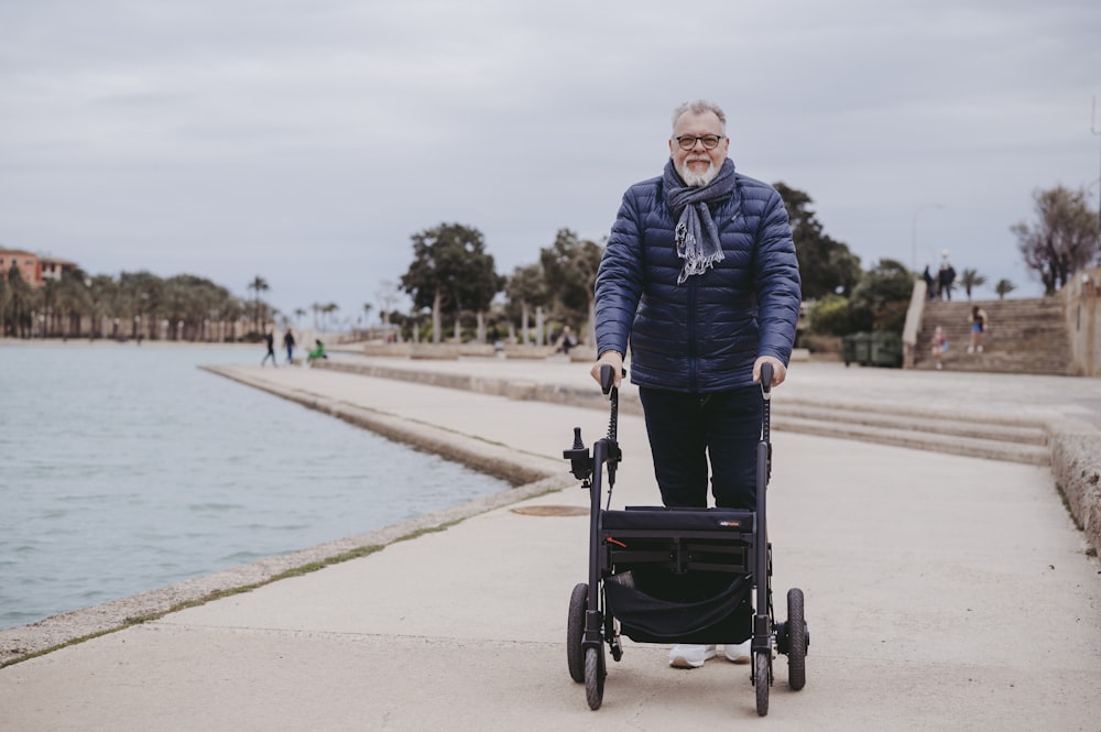 a man is walking with a stroller by the water