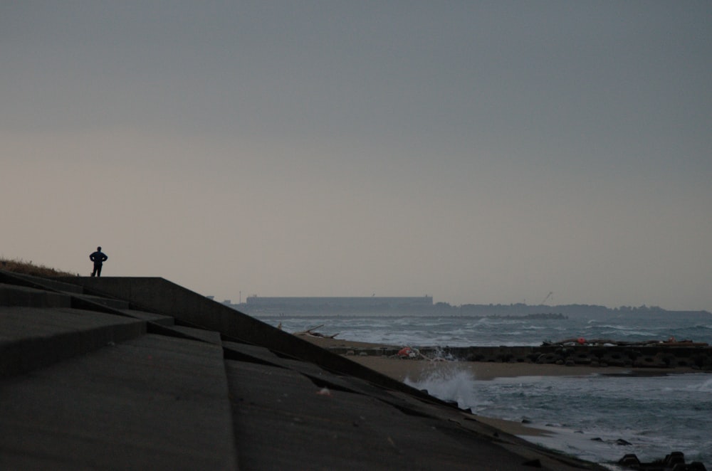 a person standing on top of a roof next to the ocean