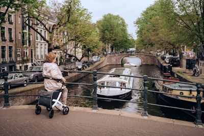a woman riding a scooter down a street next to a river
