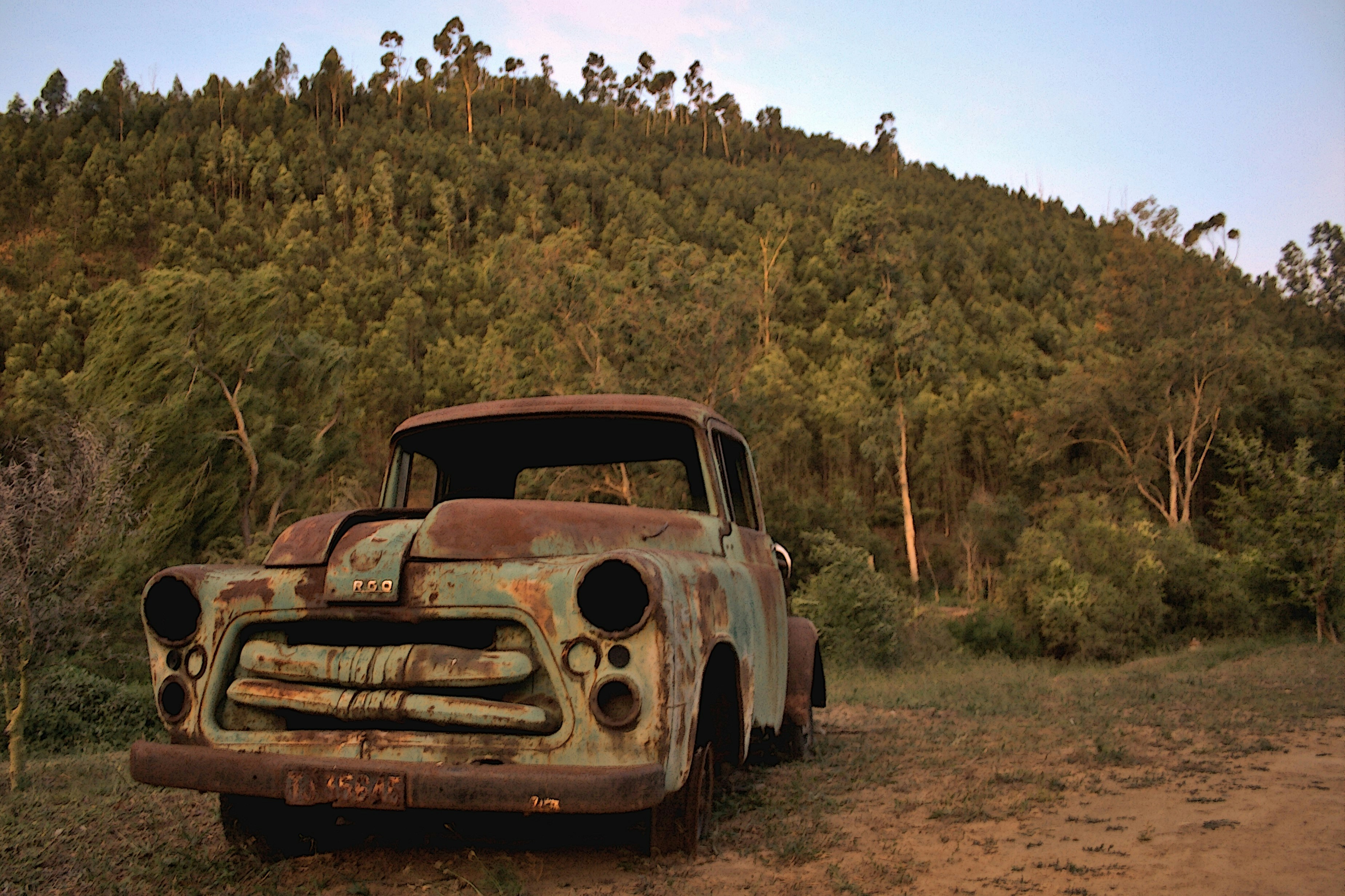 Rusted pickup truck on farm at sunset