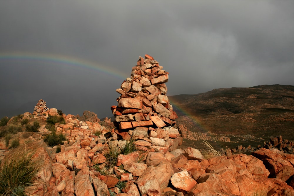 a pile of rocks with a rainbow in the background