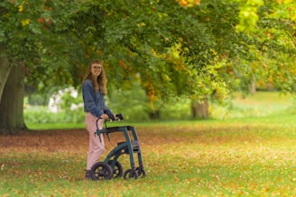 a woman standing next to a blue bike in a park