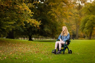 a woman sitting in a wheel chair in a park