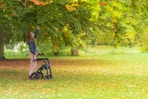 a woman standing next to a stroller in a park