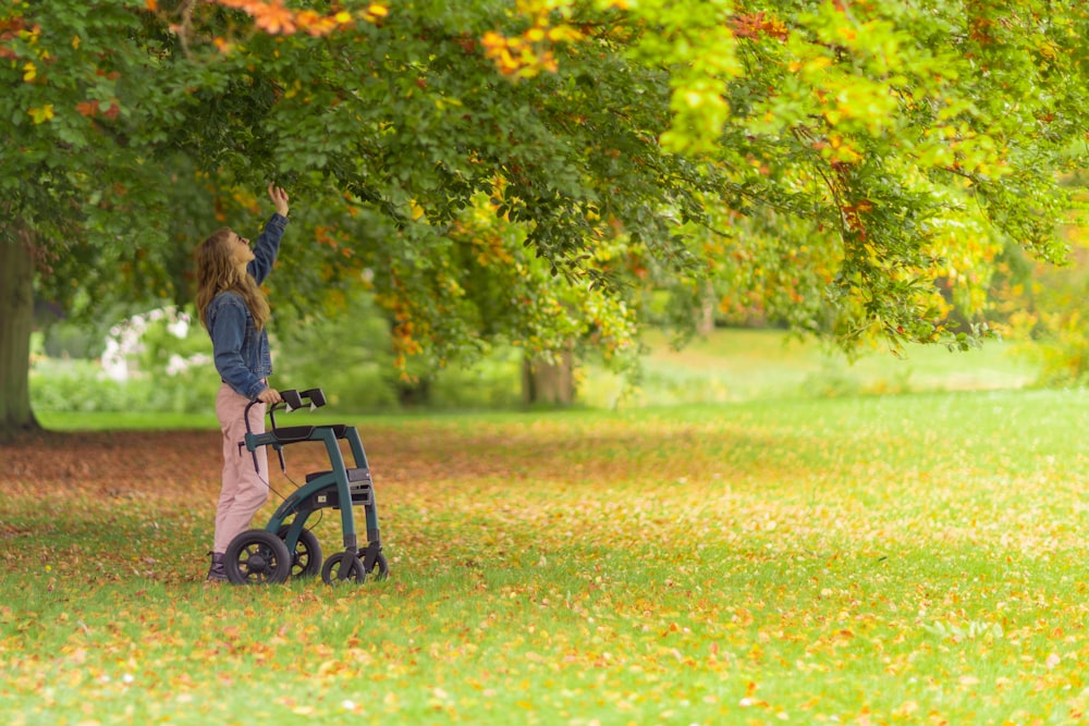 a woman standing next to a stroller in a park