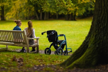 a woman sitting on a bench next to a woman in a wheelchair
