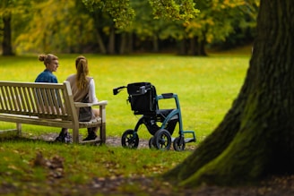a woman sitting on a bench next to a woman in a wheelchair