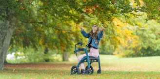 a woman standing next to a blue stroller in a park