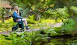 a woman sitting in a wheel chair in the woods
