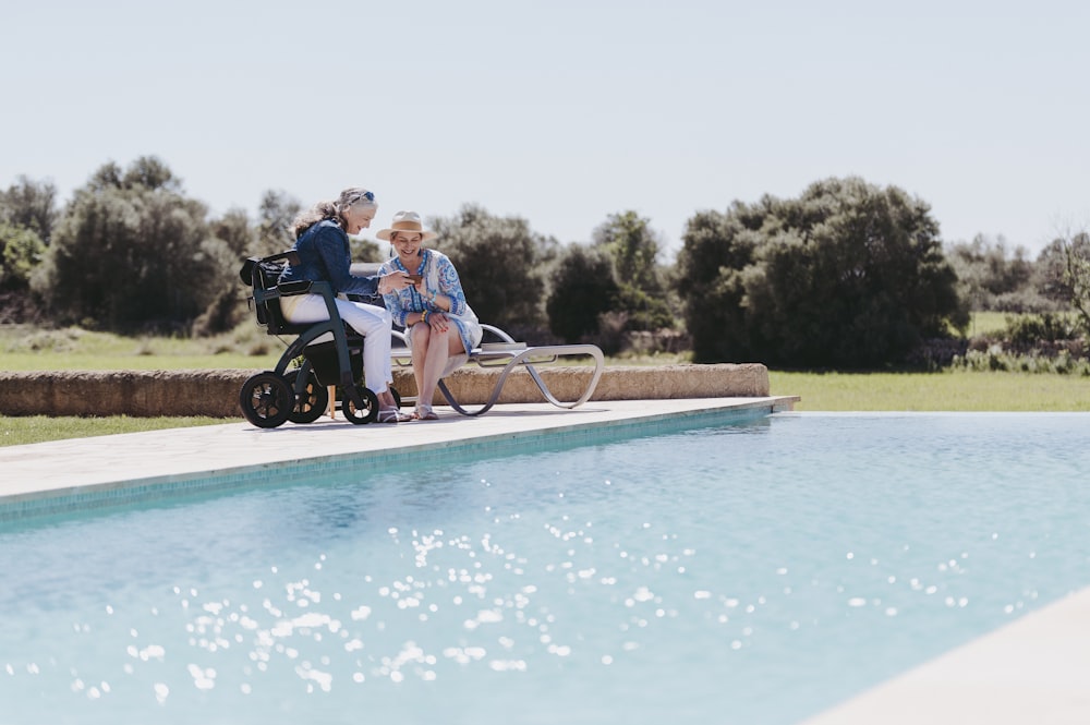 Un par de mujeres sentadas en una motocicleta junto a una piscina