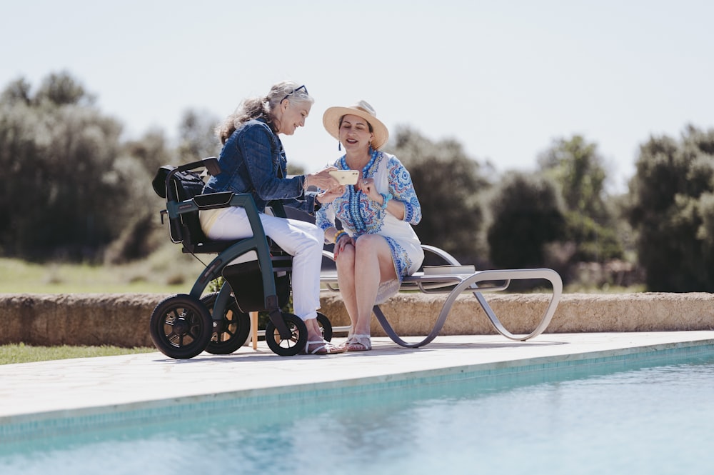 two older women sitting next to a swimming pool