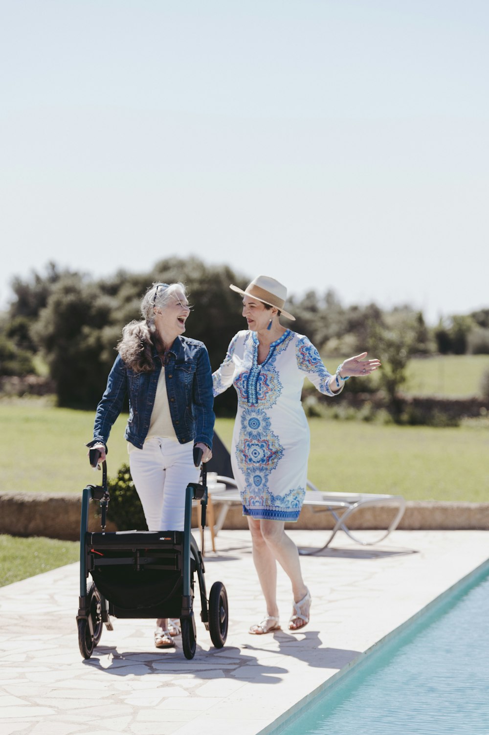 two older women walking next to a pool