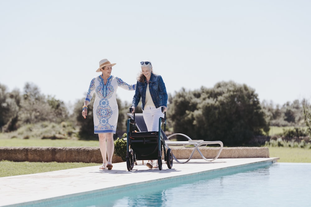 a couple of women walking next to a pool