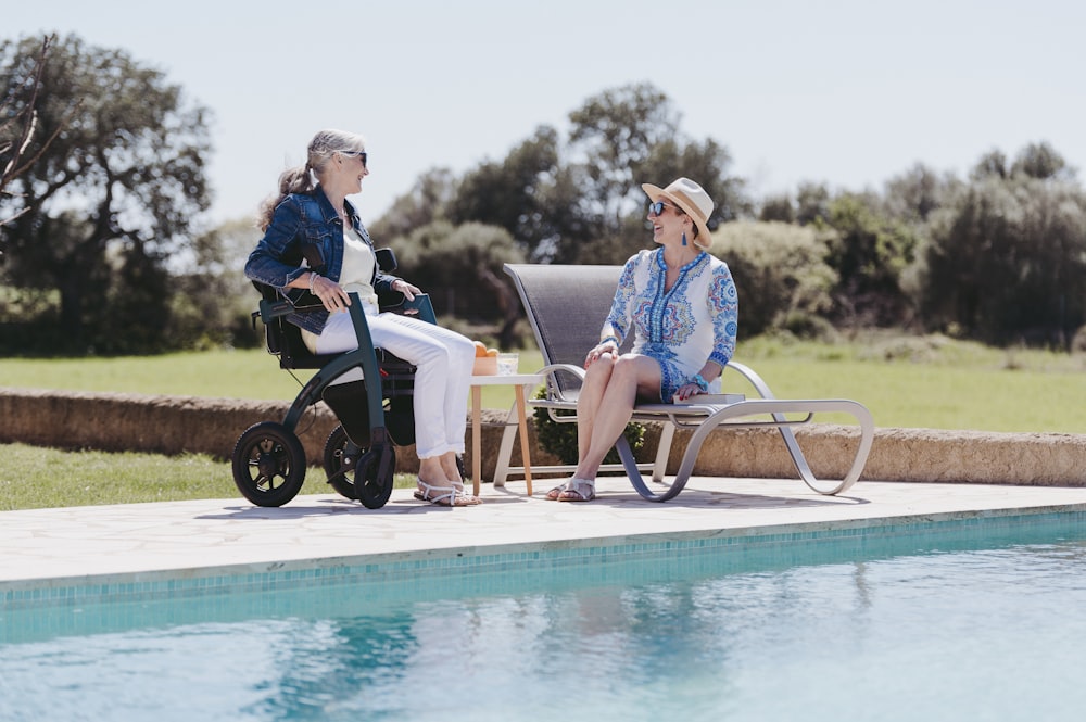 Dos mujeres sentadas una al lado de la otra cerca de una piscina