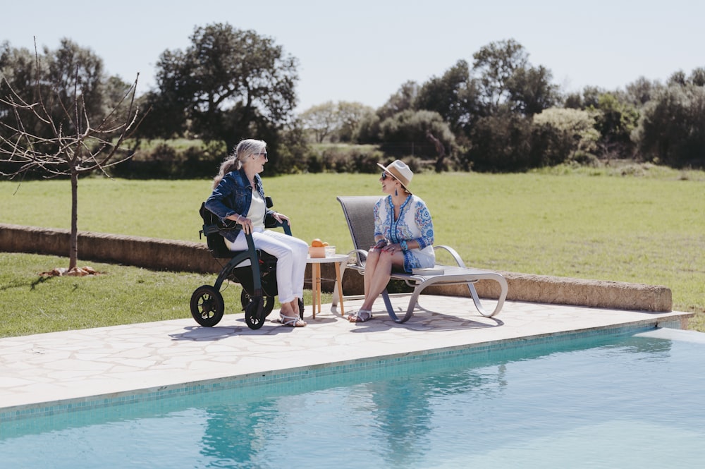 Un par de mujeres sentadas junto a una piscina