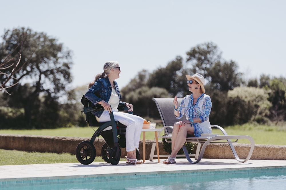 a couple of women sitting next to a pool