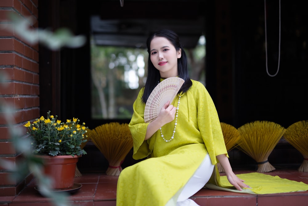 a woman sitting on a step holding a fan