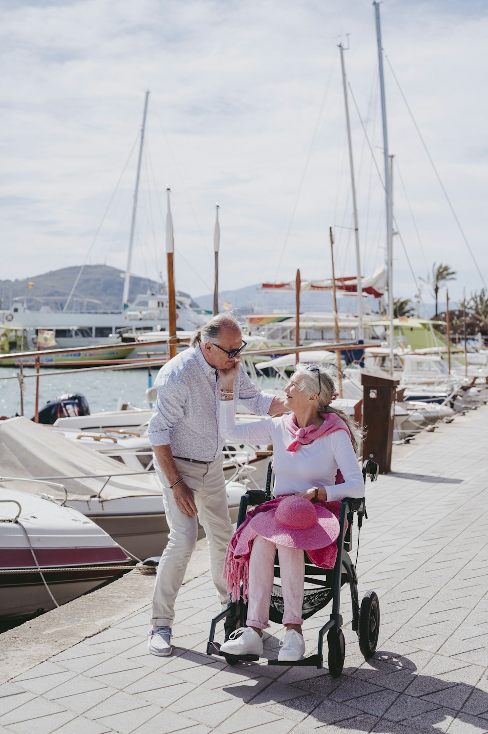 a man standing next to a woman in a wheel chair