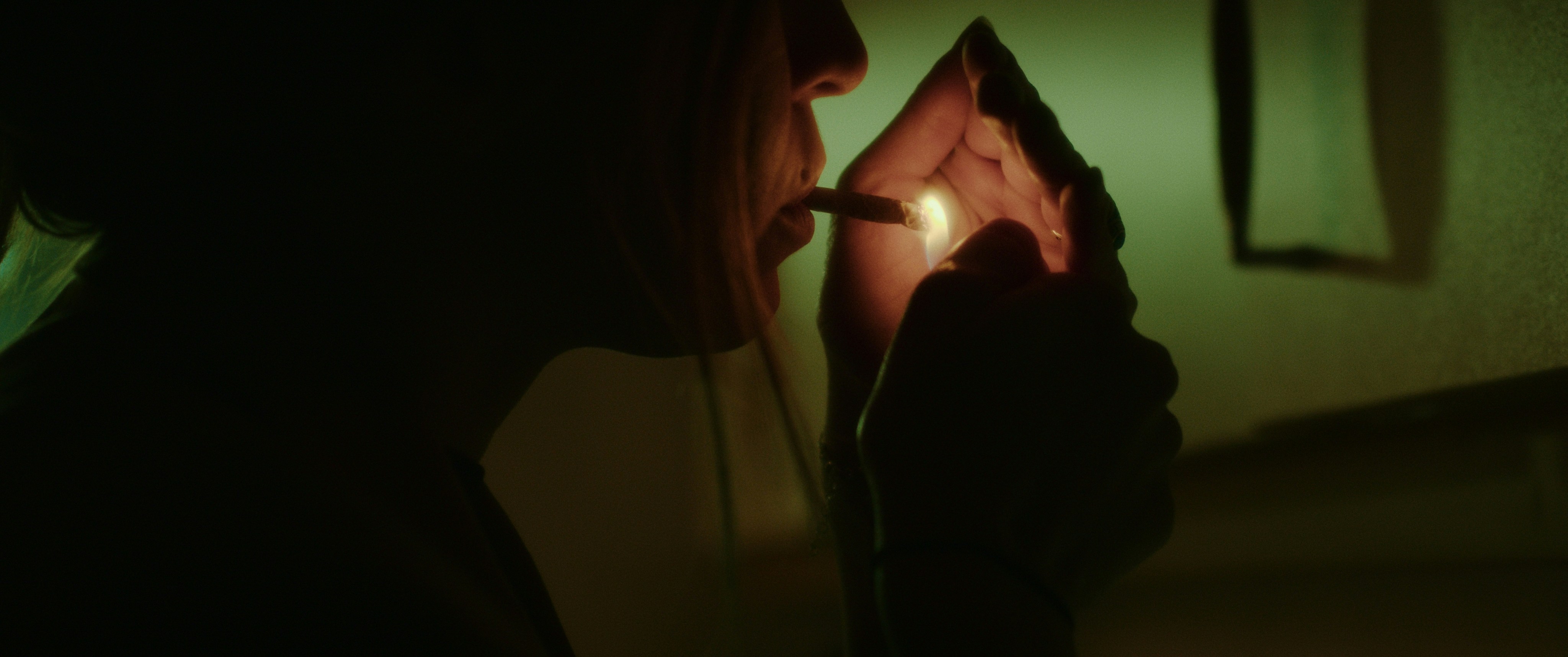 a woman lighting a cigarette in a dark room