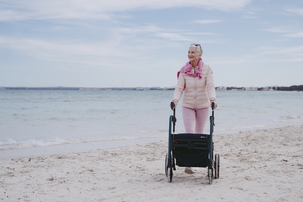 a woman pushing a stroller on the beach