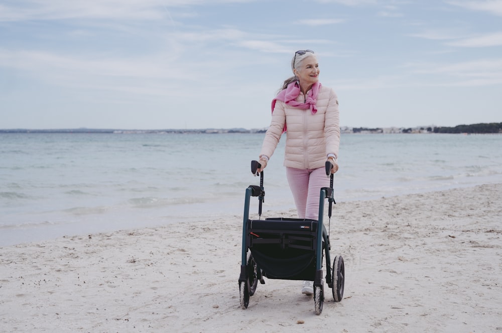 a woman pushing a stroller on the beach