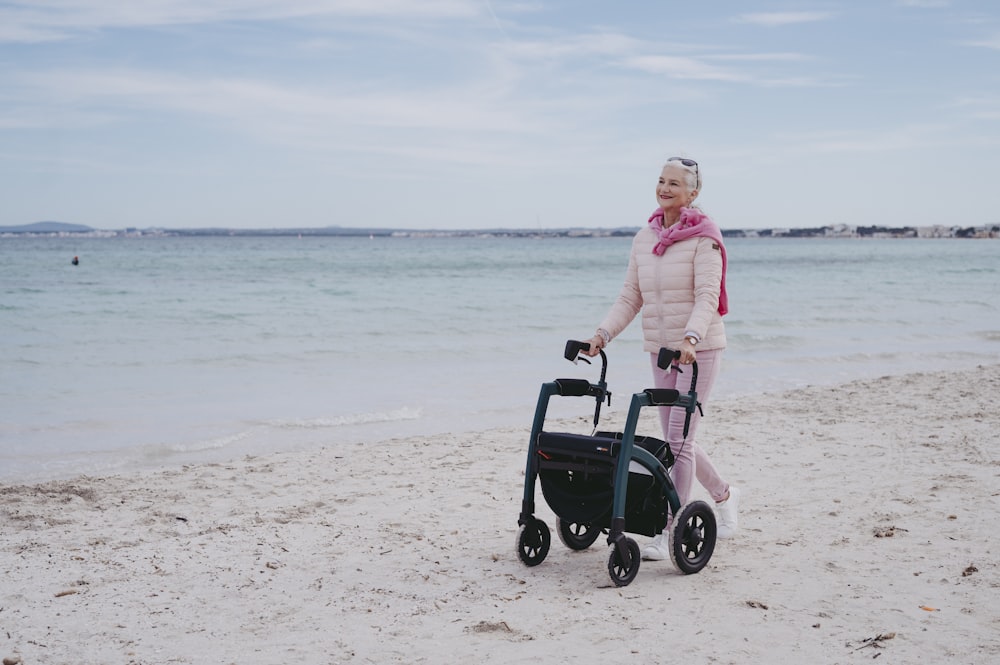 a woman is walking on the beach with a stroller