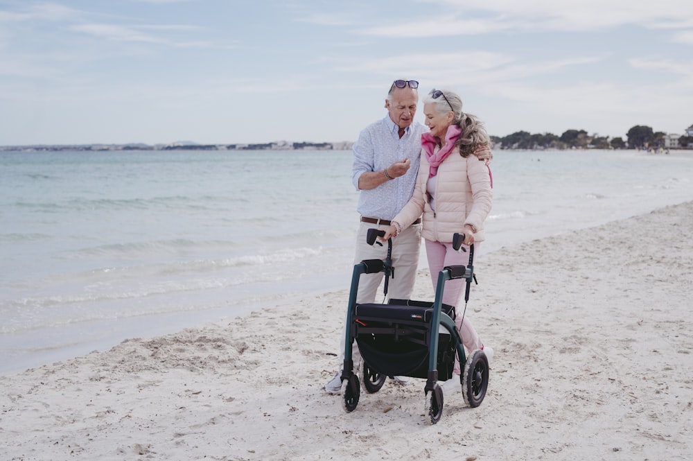 a man and woman standing on a beach next to the ocean