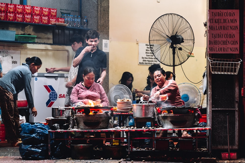 a group of people standing around a table filled with food